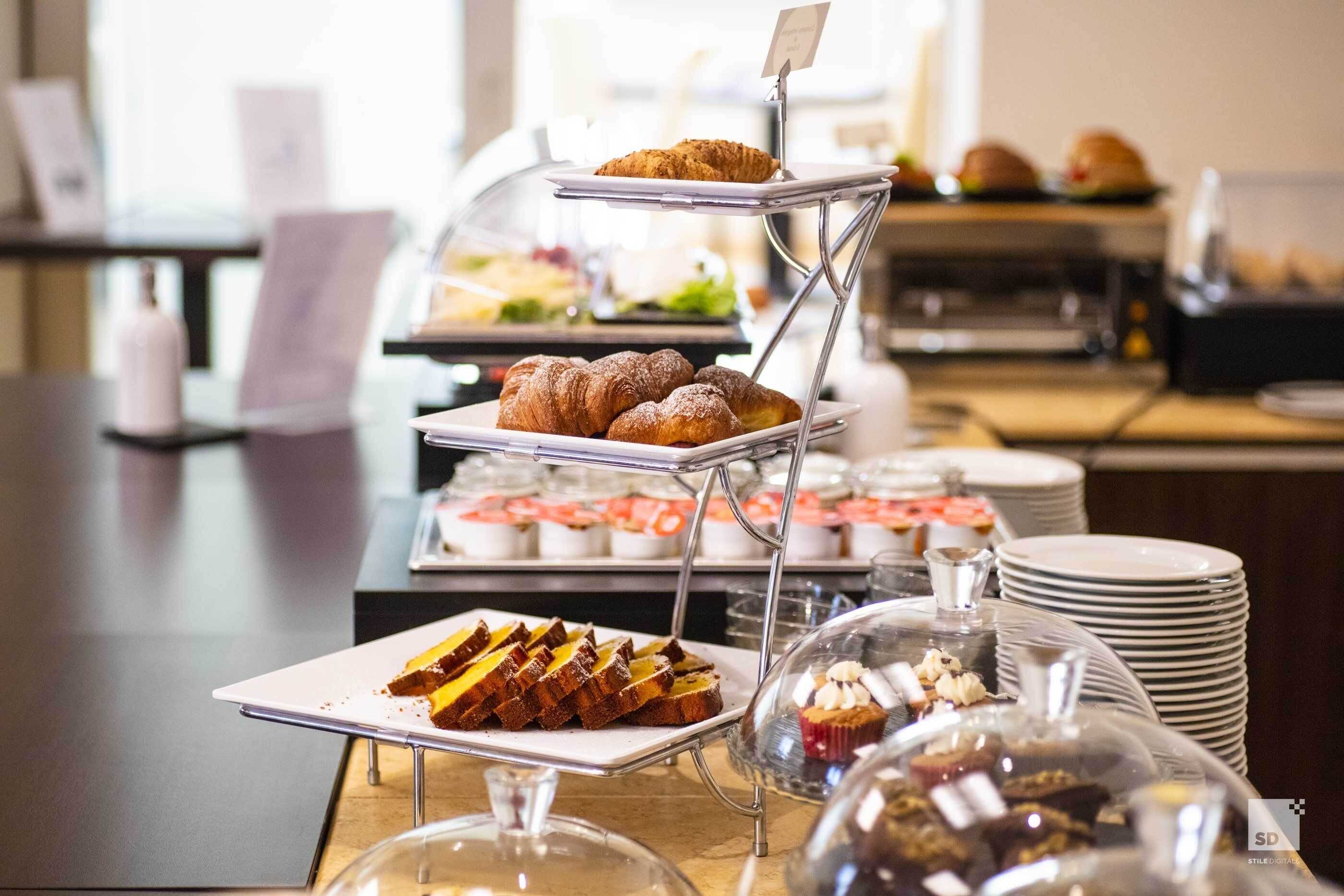 Un buffet proposant une variété de plats, notamment des pâtisseries, des sandwichs et des desserts.