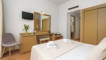 A hotel room with a bed, a desk, a chair, a TV, and a wardrobe.