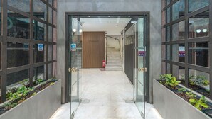 A modern building entrance with glass doors, a fire extinguisher, and a staircase in the background. - Parnon Hotel (Athens)
