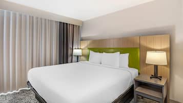A hotel room with a large bed, two bedside lamps, a headboard, and a carpeted floor.