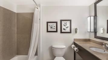 A modern bathroom with a bathtub, toilet, sink, and framed artwork on the wall.