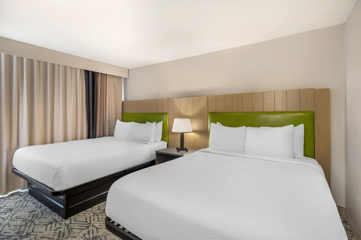 Two single beds with green headboards, a bedside table with a lamp, and a patterned carpet.