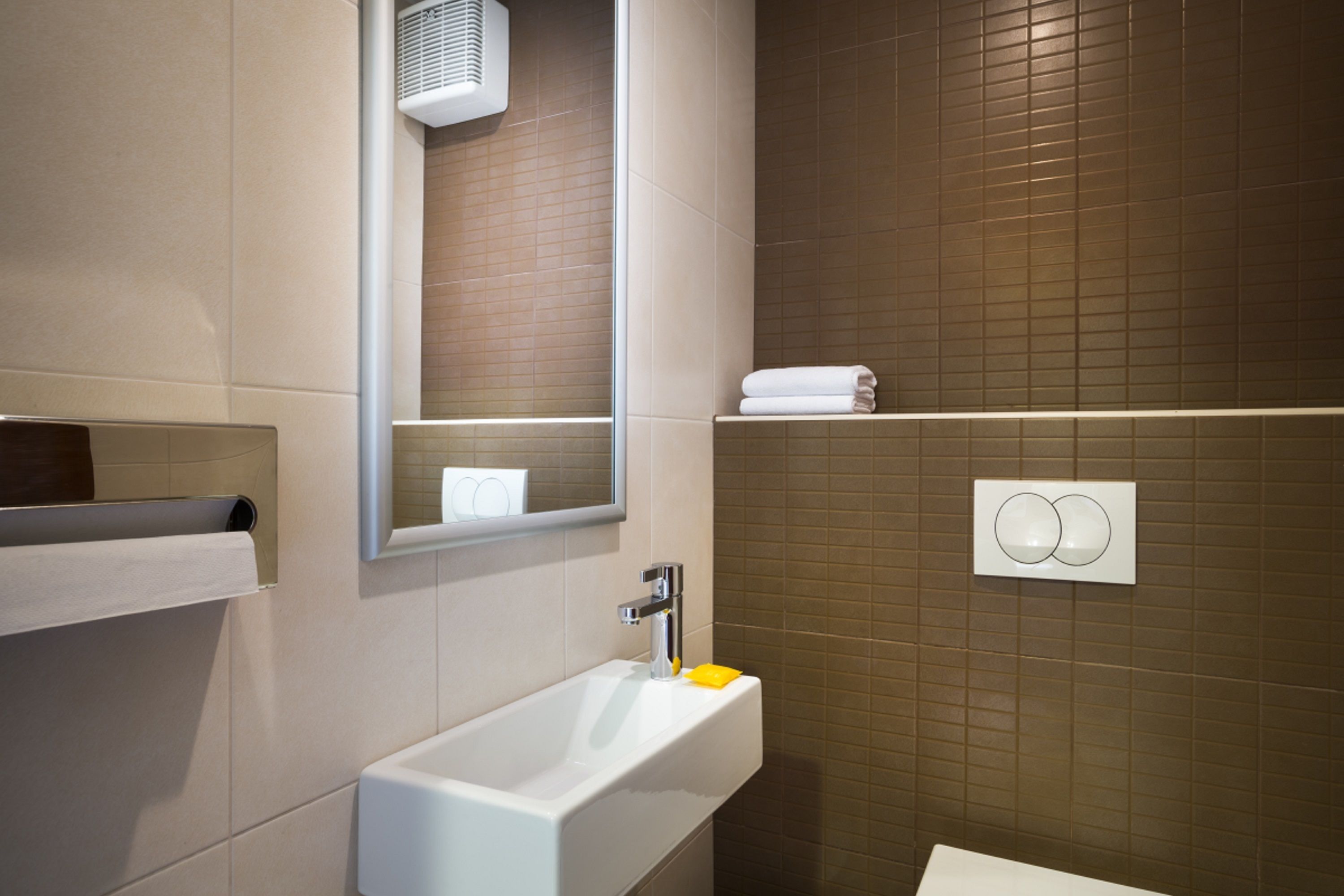 A modern bathroom with a white sink, a mirror, and a towel rack.
