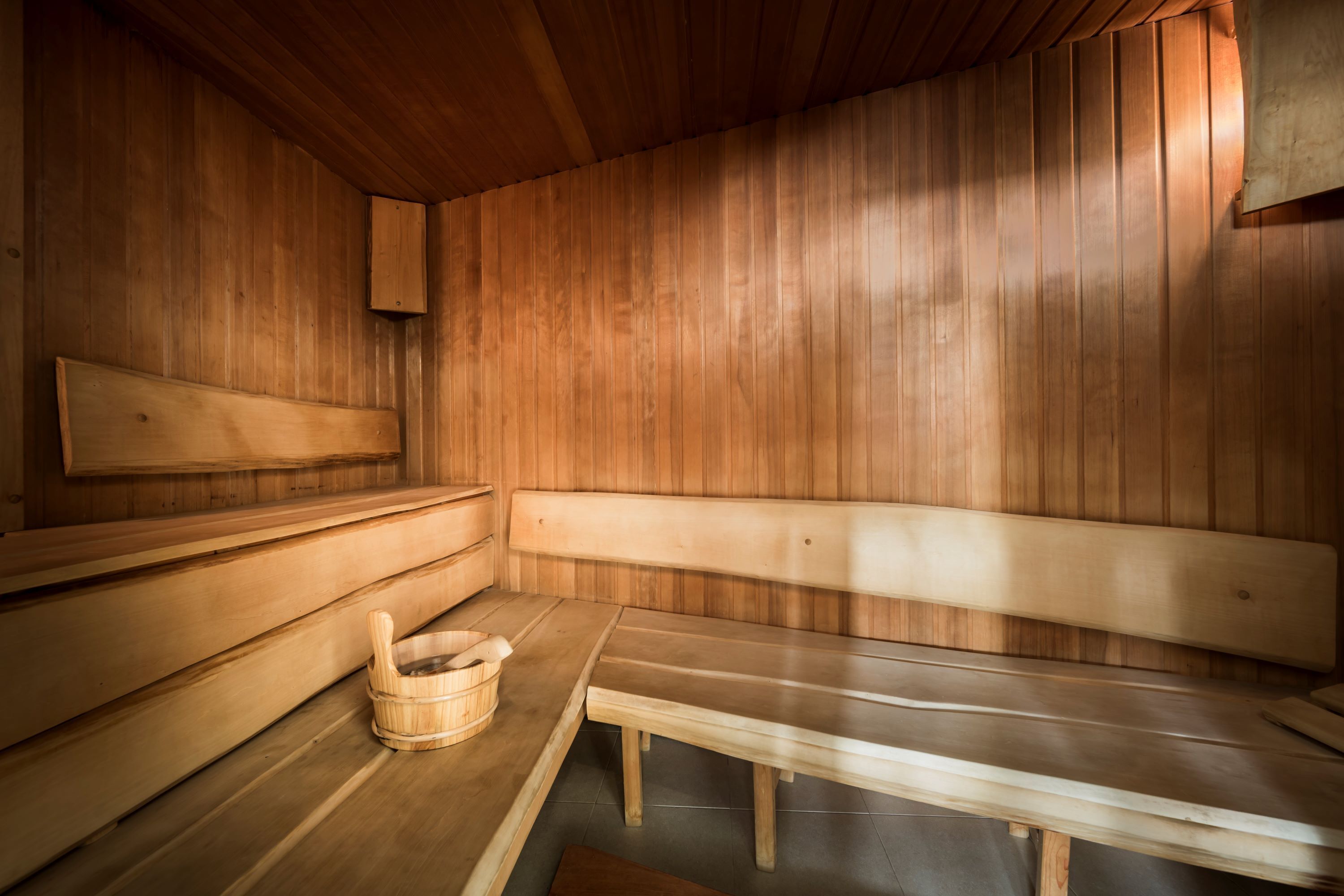 Un sauna en bois, avec des bancs et un seau en bois.
