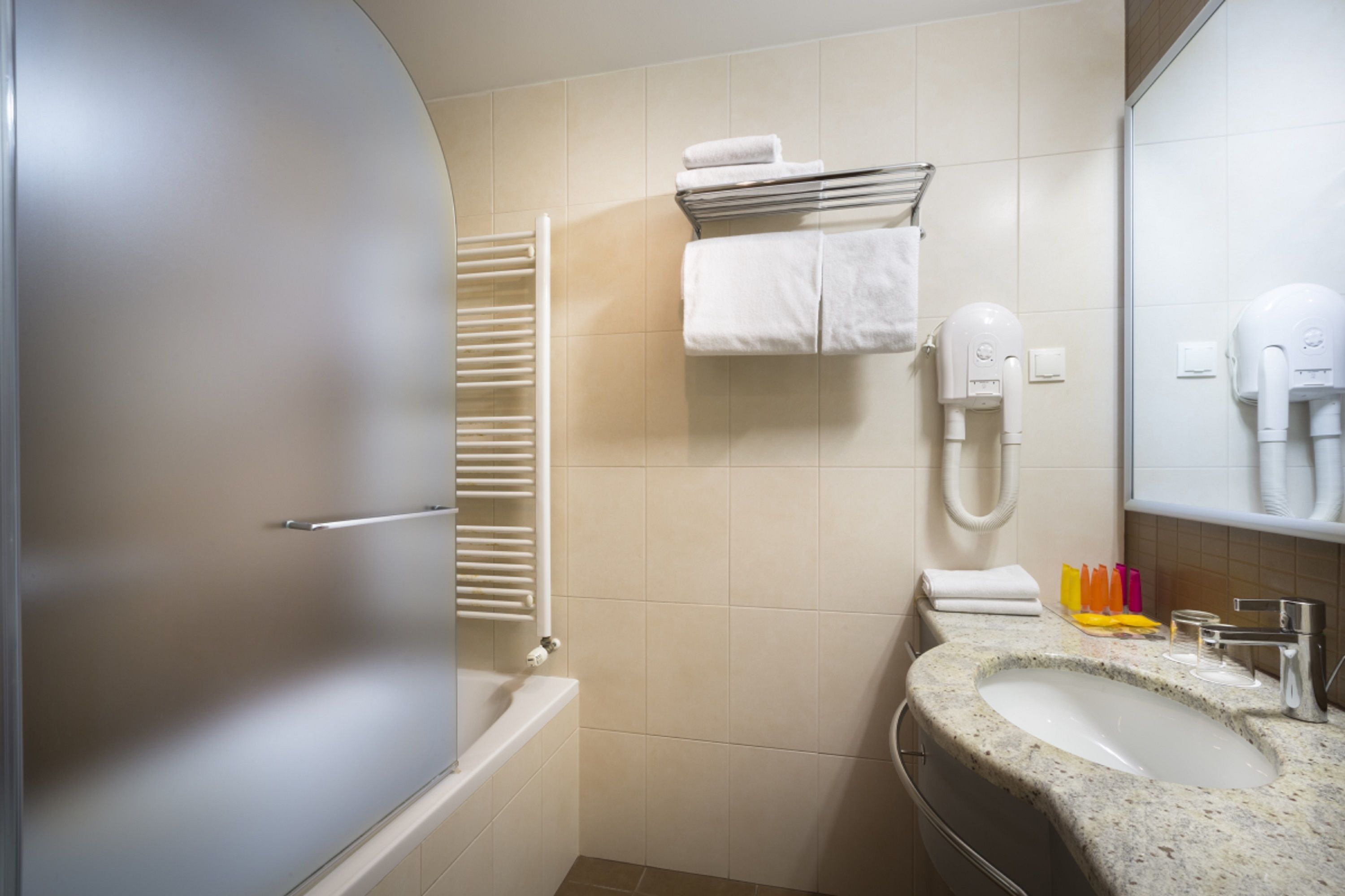 A bathroom with a bathtub, a sink, a towel rack, and a hairdryer.