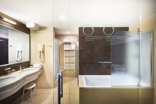 A modern bathroom with a glass-enclosed shower, a large mirror, and a vanity with a sink and stool.
