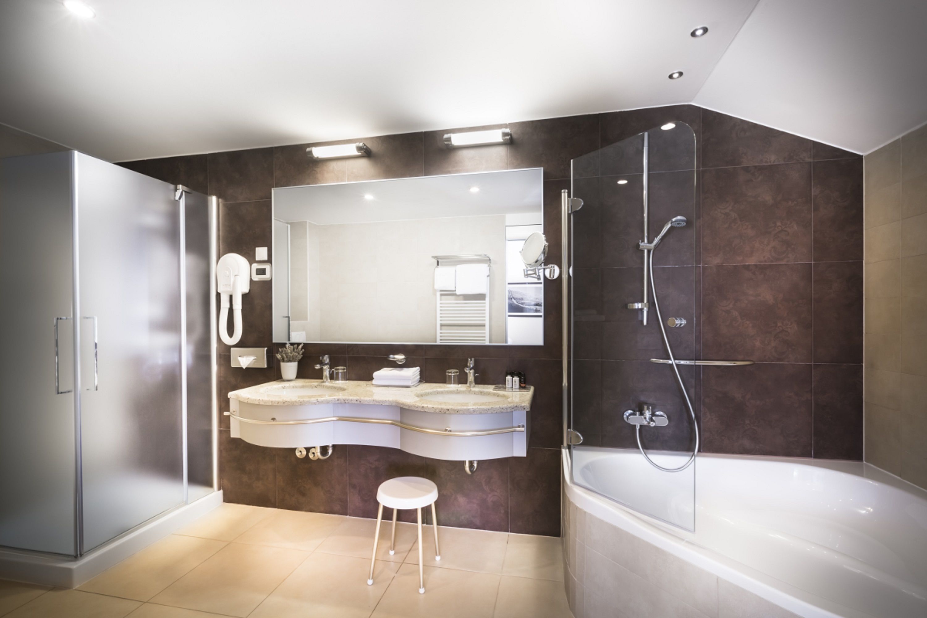 A modern bathroom with dual sinks, a large mirror, a walk-in shower, and a separate bathtub.