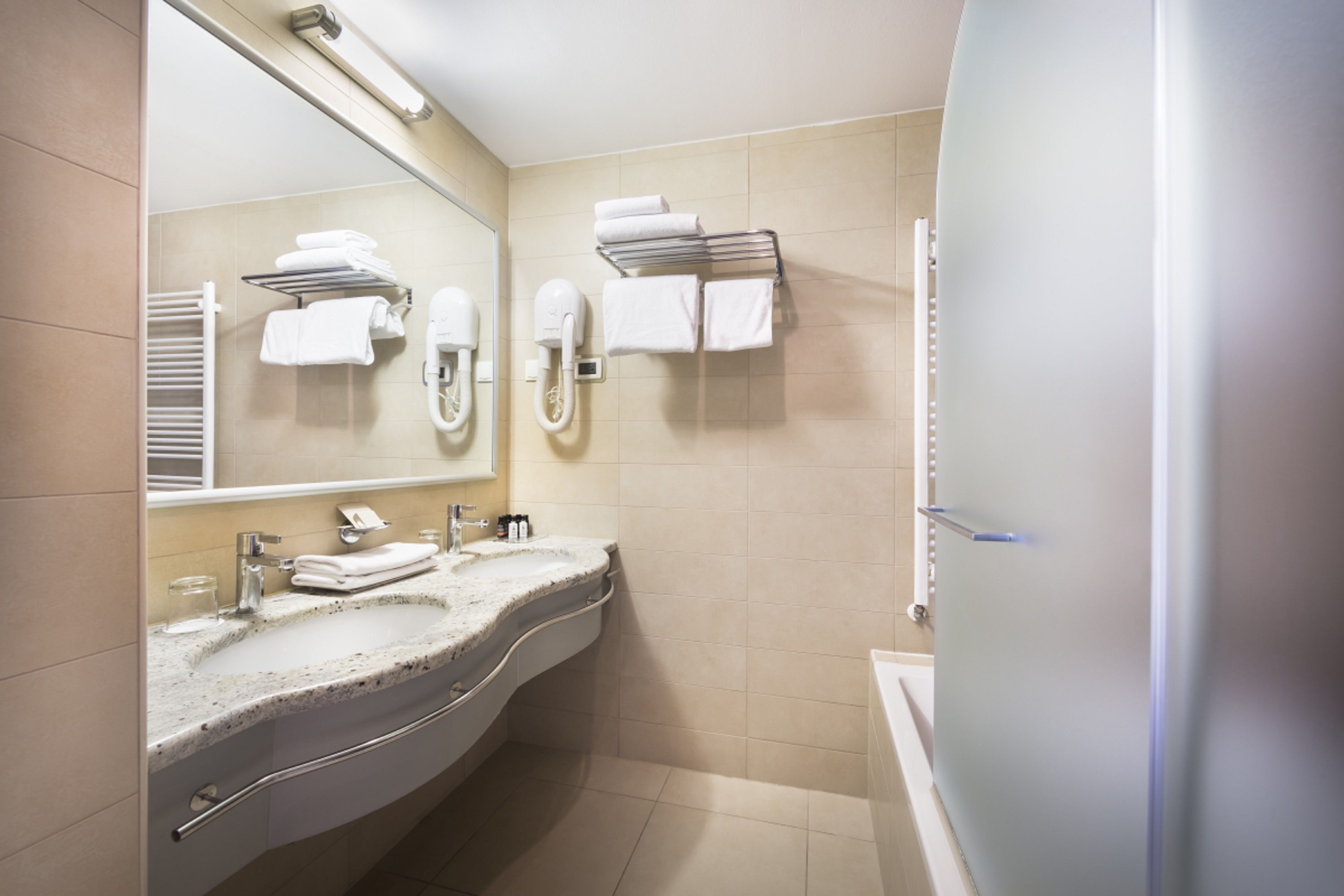 A modern bathroom with a sink, mirror, towel rack, and shower.