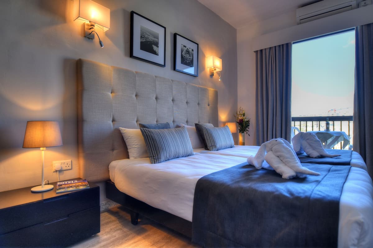 A hotel room with a large bed, bedside tables, and a view of a bridge through the window.
