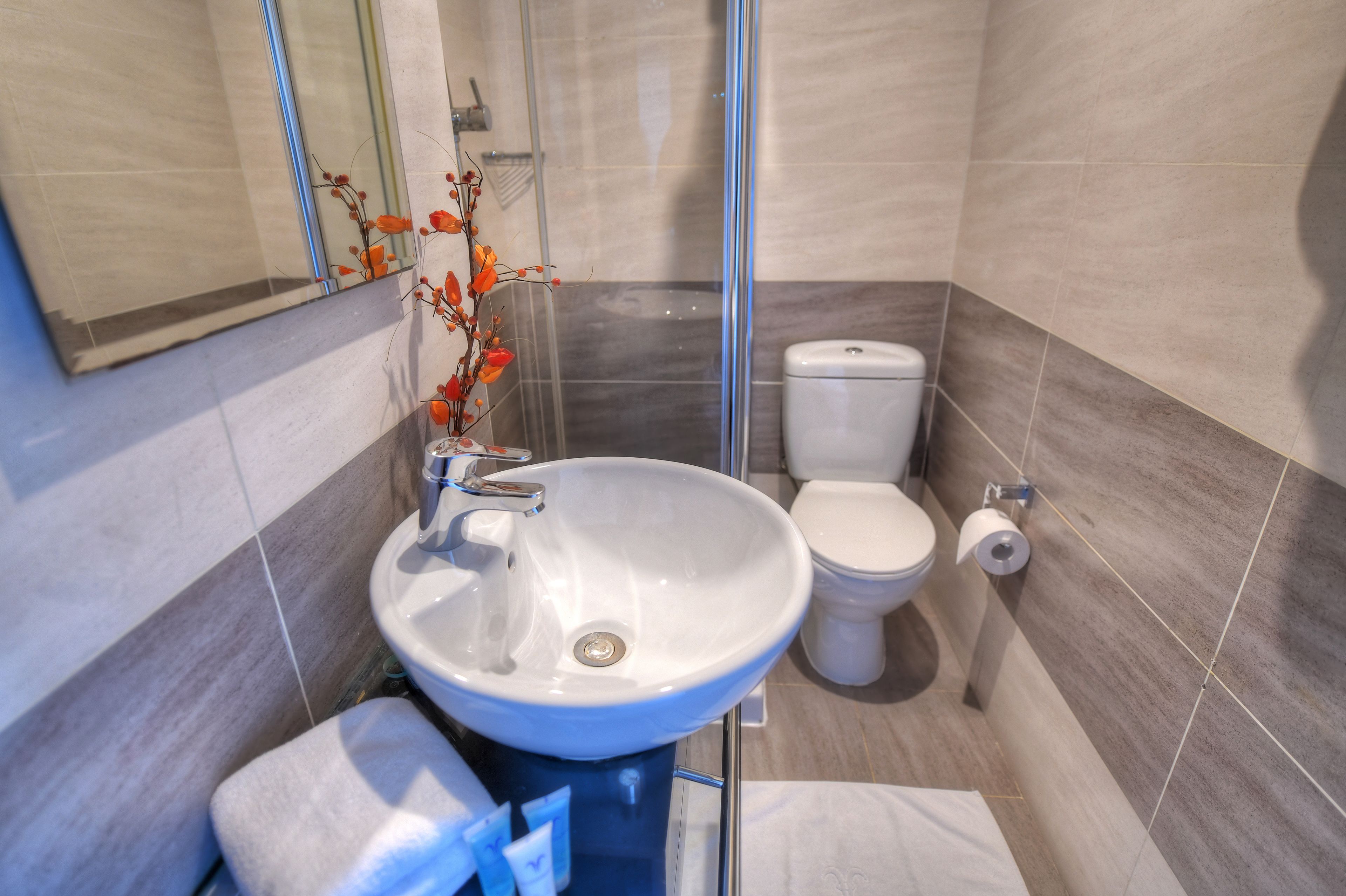 A modern bathroom with a white sink, toilet, and glass shower enclosure.