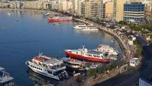 A marina with several boats docked, a waterfront promenade, and buildings in the background. - St Julian's Bay Hotel (St. Julian's)