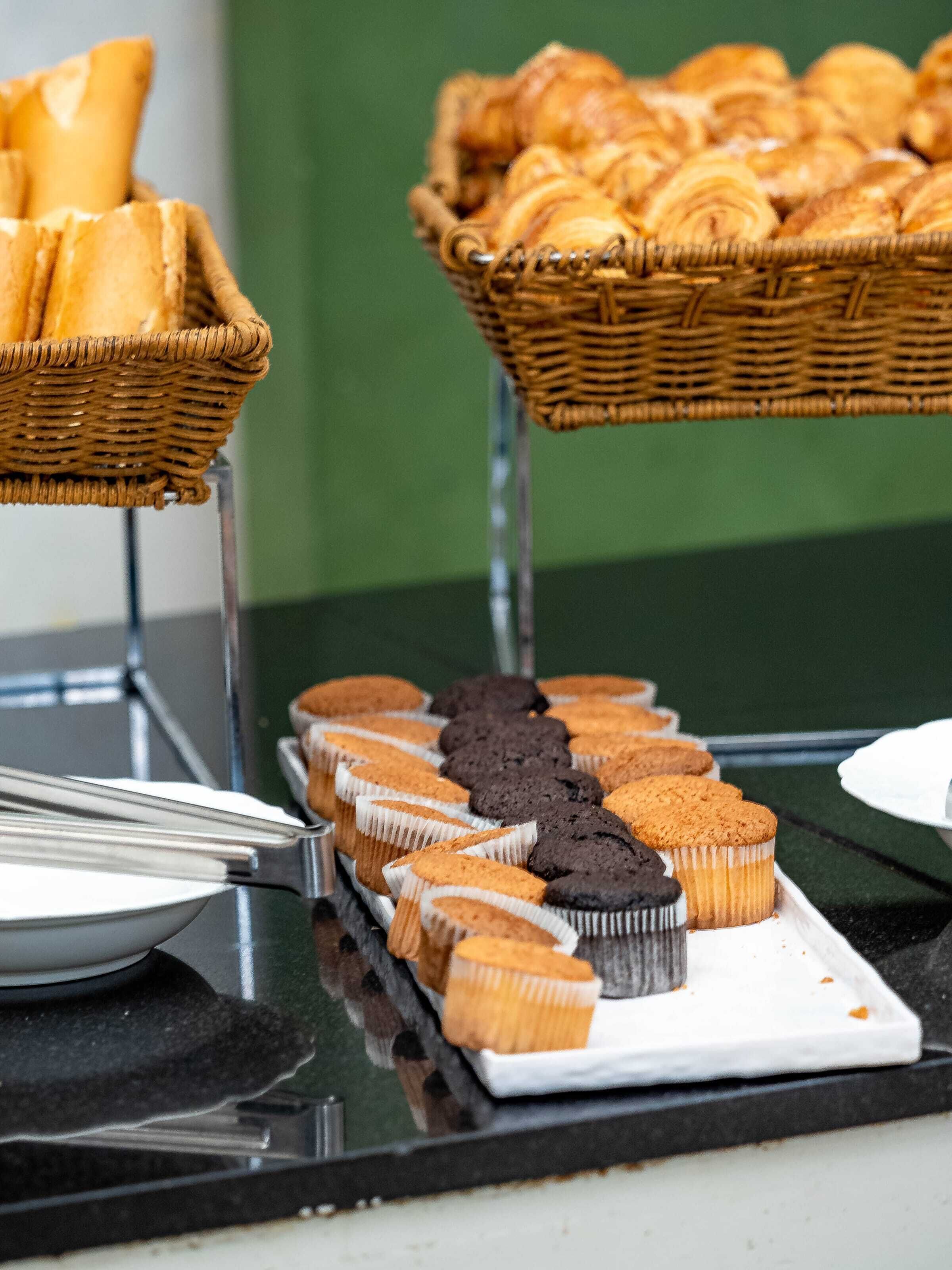 A buffet with various baked goods including bread, croissants, and muffins.