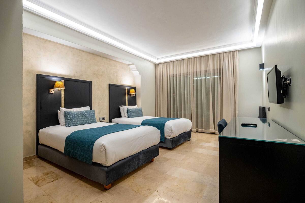 Une chambre d’hôtel avec deux lits, un bureau et une télévision.