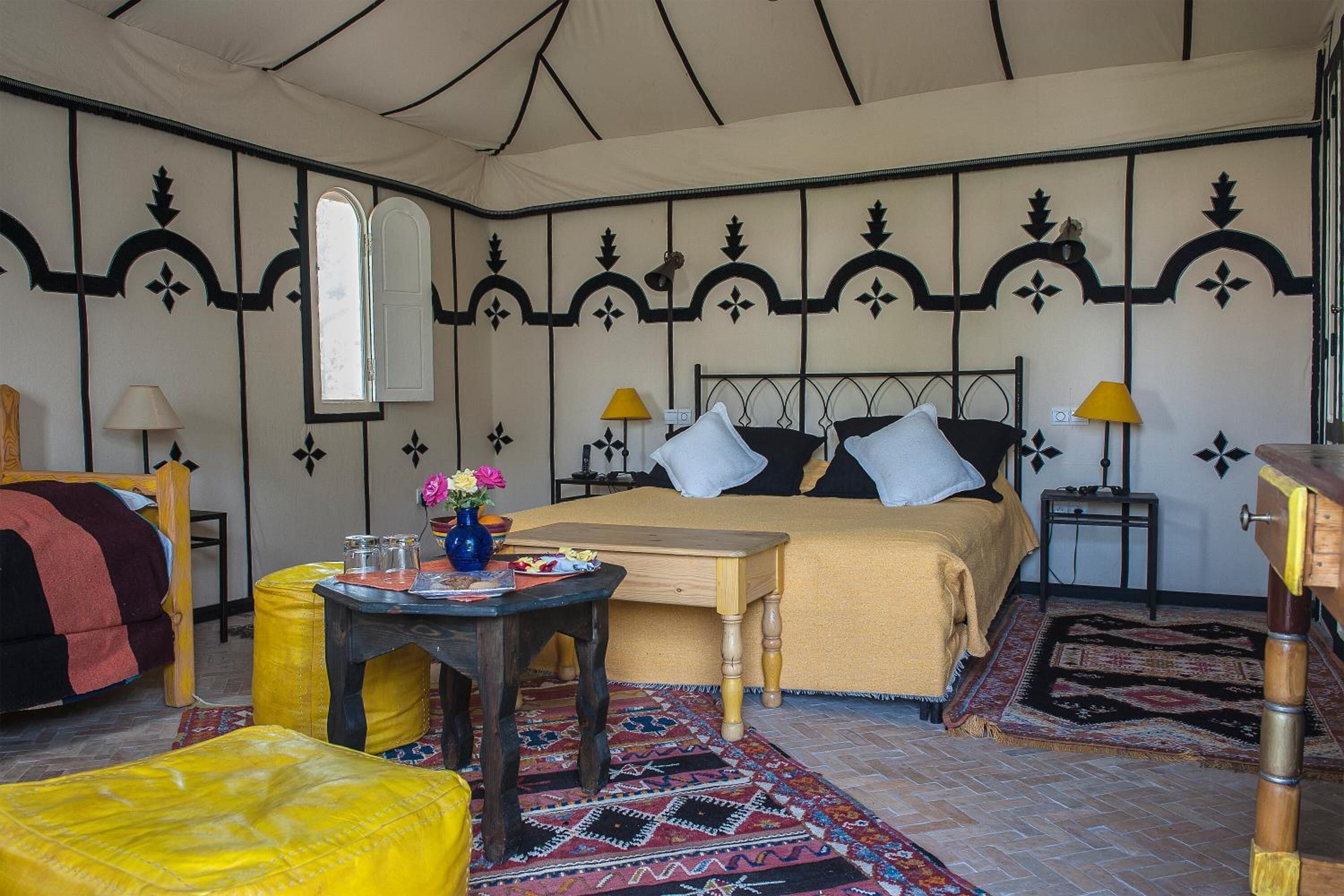 A cozy room with a bed, a small table, a chair, and a window.