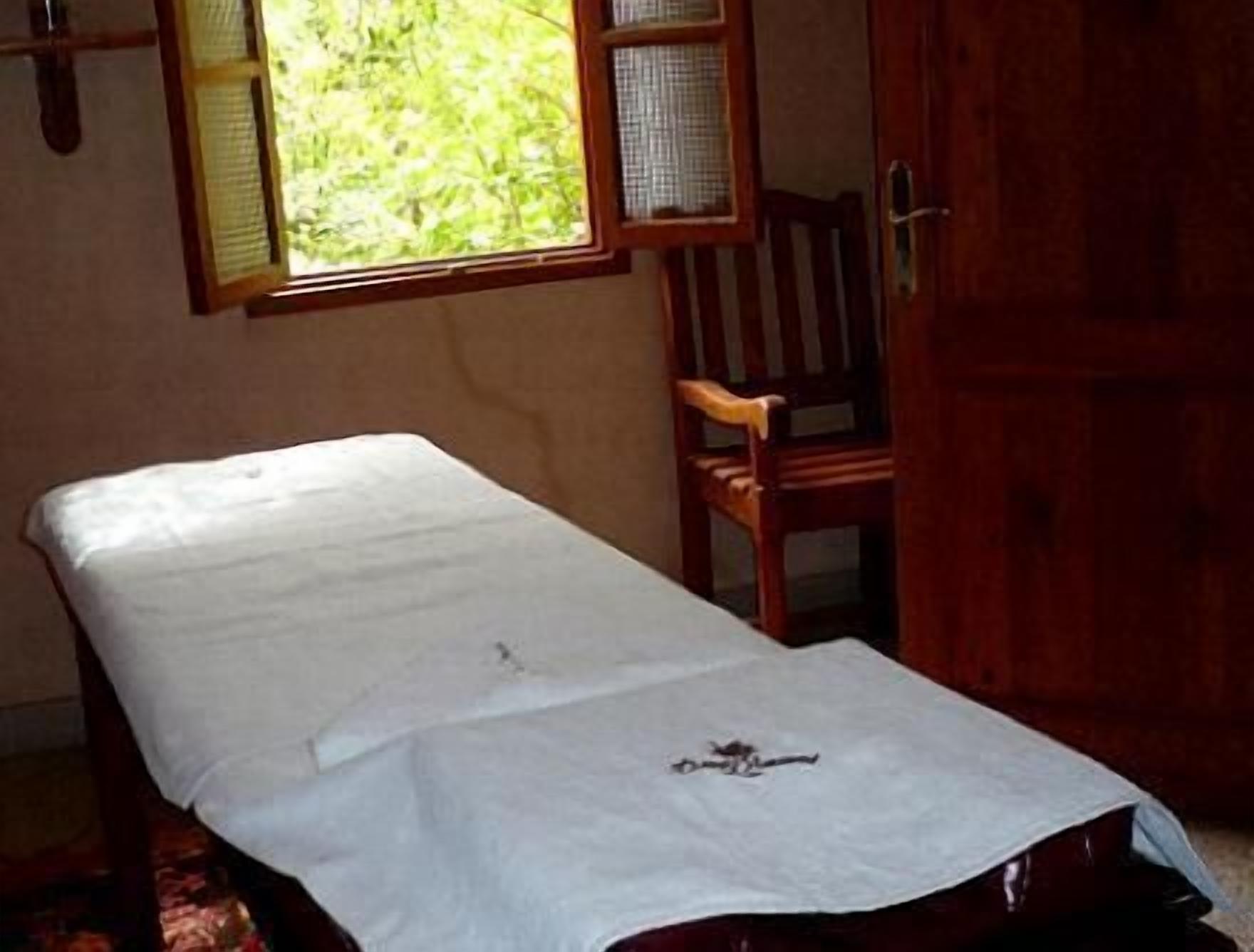 Une pièce comprenant un lit, une chaise en bois et une armoire.