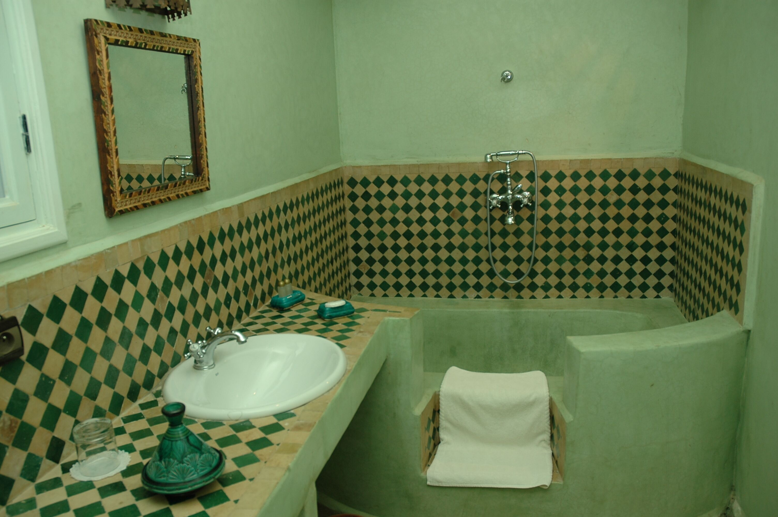 A bathroom with a checkered floor, a sink, a mirror, and a bathtub.
