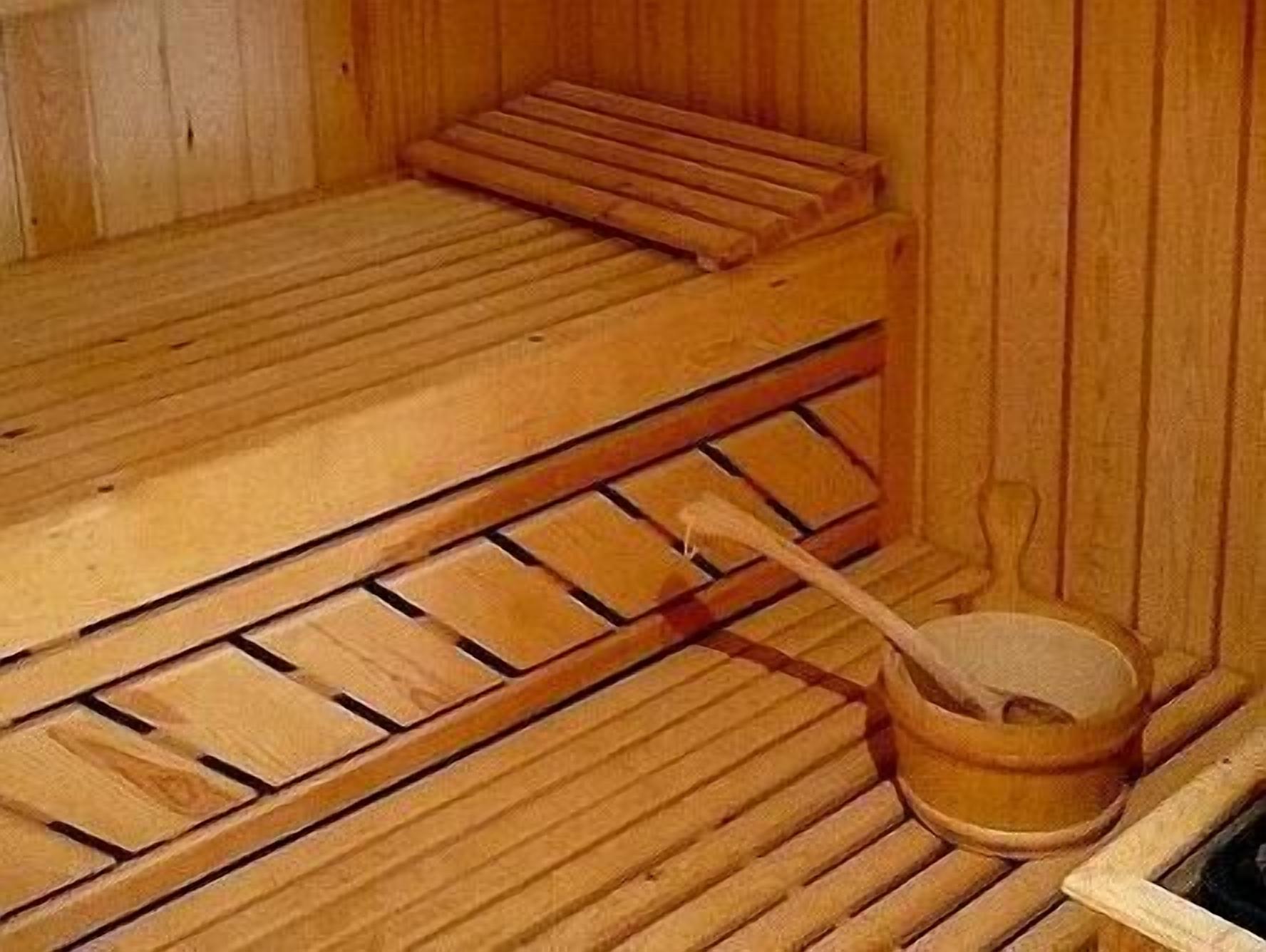 Eine Holzsauna mit einer Bank, einem Holzfass und einem Holzlöffel.
