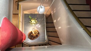 A modern staircase with a red cone-shaped object and a small plant on a shelf. - Logis Hôtel du Midi - Saint Etienne Sud (Saint-Etienne)