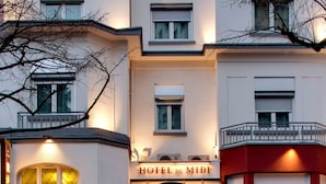 A hotel with a prominent entrance, multiple windows, and a balcony. - Logis Hôtel du Midi - Saint Etienne Sud (Saint-Etienne)