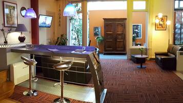 A hotel lobby with a reception desk, bar area, and seating.