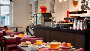 A breakfast setting with tables, chairs, and a buffet counter. - Logis Hôtel du Midi - Saint Etienne Sud (Saint-Etienne)
