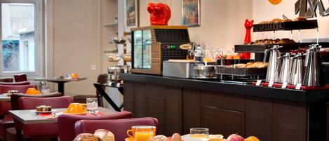 Un ambiente para el desayuno con mesas, sillas y una barra de buffet.