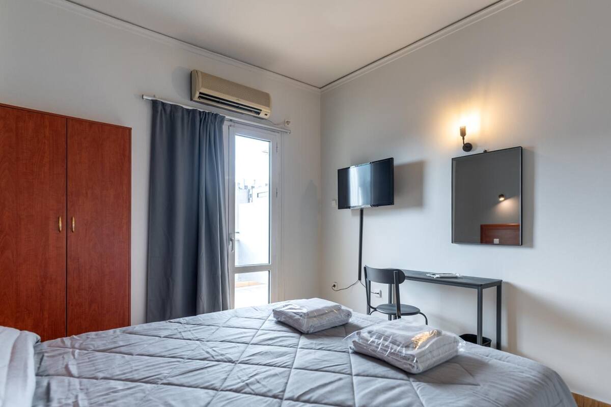 A hotel room with a bed, a desk, a TV, and a wardrobe.