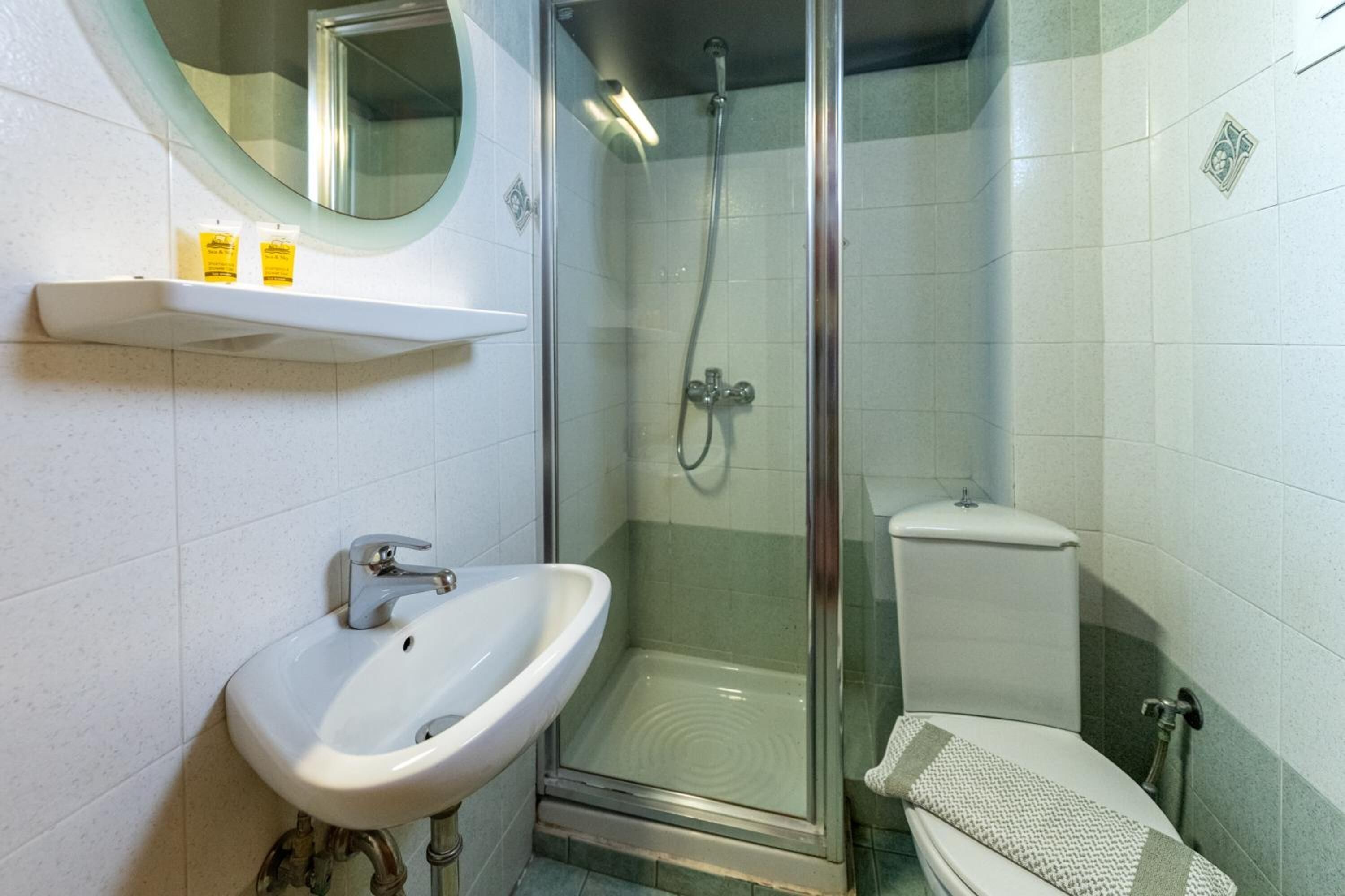 A bathroom with a white sink, a glass-enclosed shower, and a toilet.