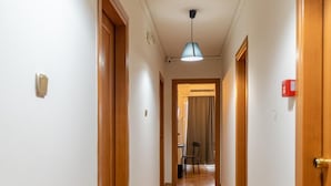 Un pasillo con puertas de madera, suelo de baldosas y una lámpara en el techo.