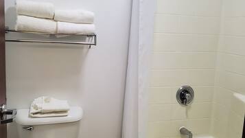 A bathroom with a toilet, a shower with a curtain, and a shelf with towels.