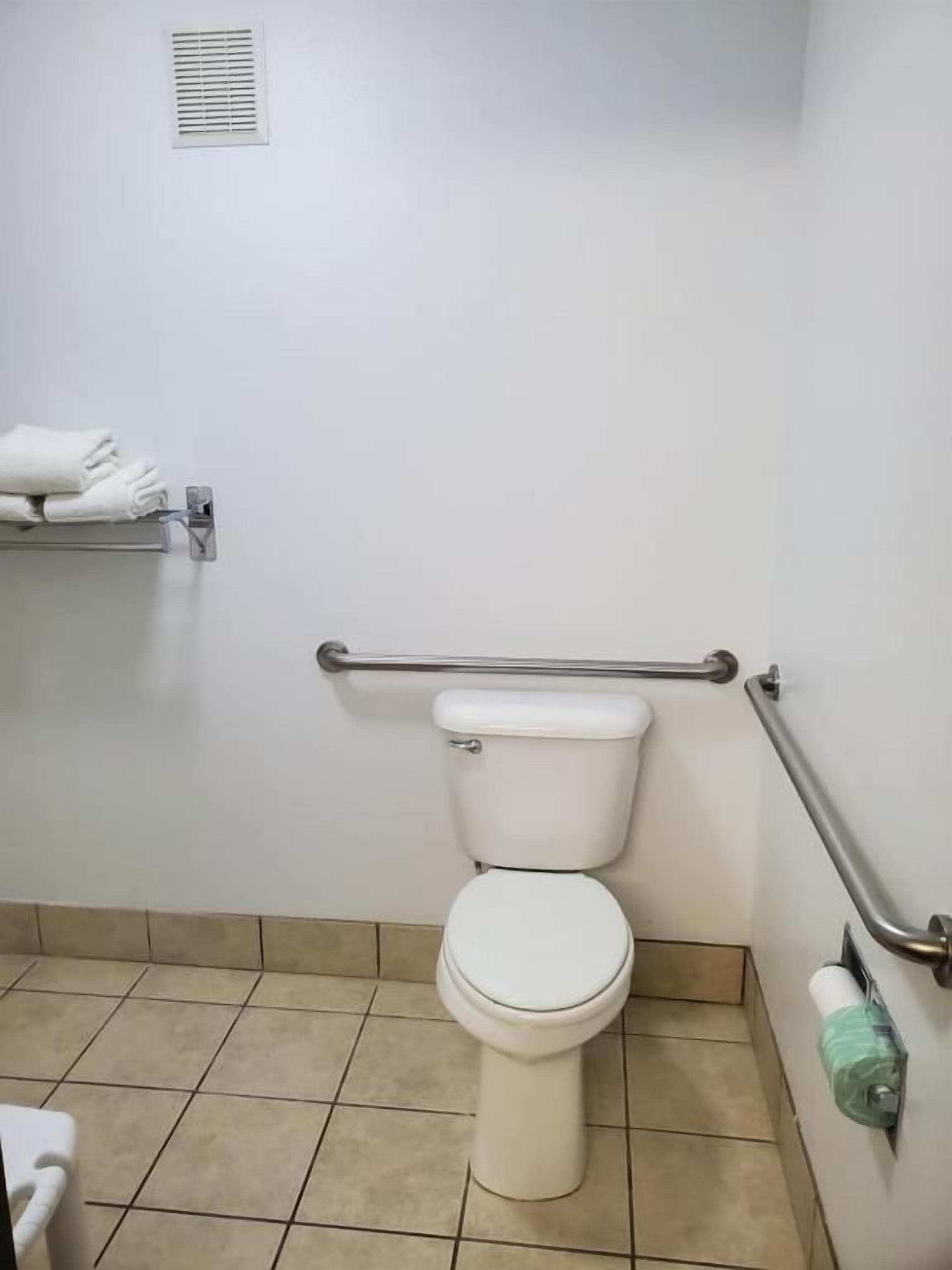 Baño estándar con inodoro, barra de apoyo y toallero.