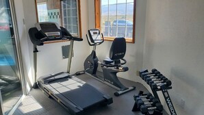 A home gym with a treadmill, an elliptical, and a set of dumbbells.