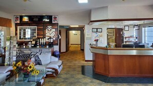 A hotel lobby with a reception desk, seating area, and a coffee station.