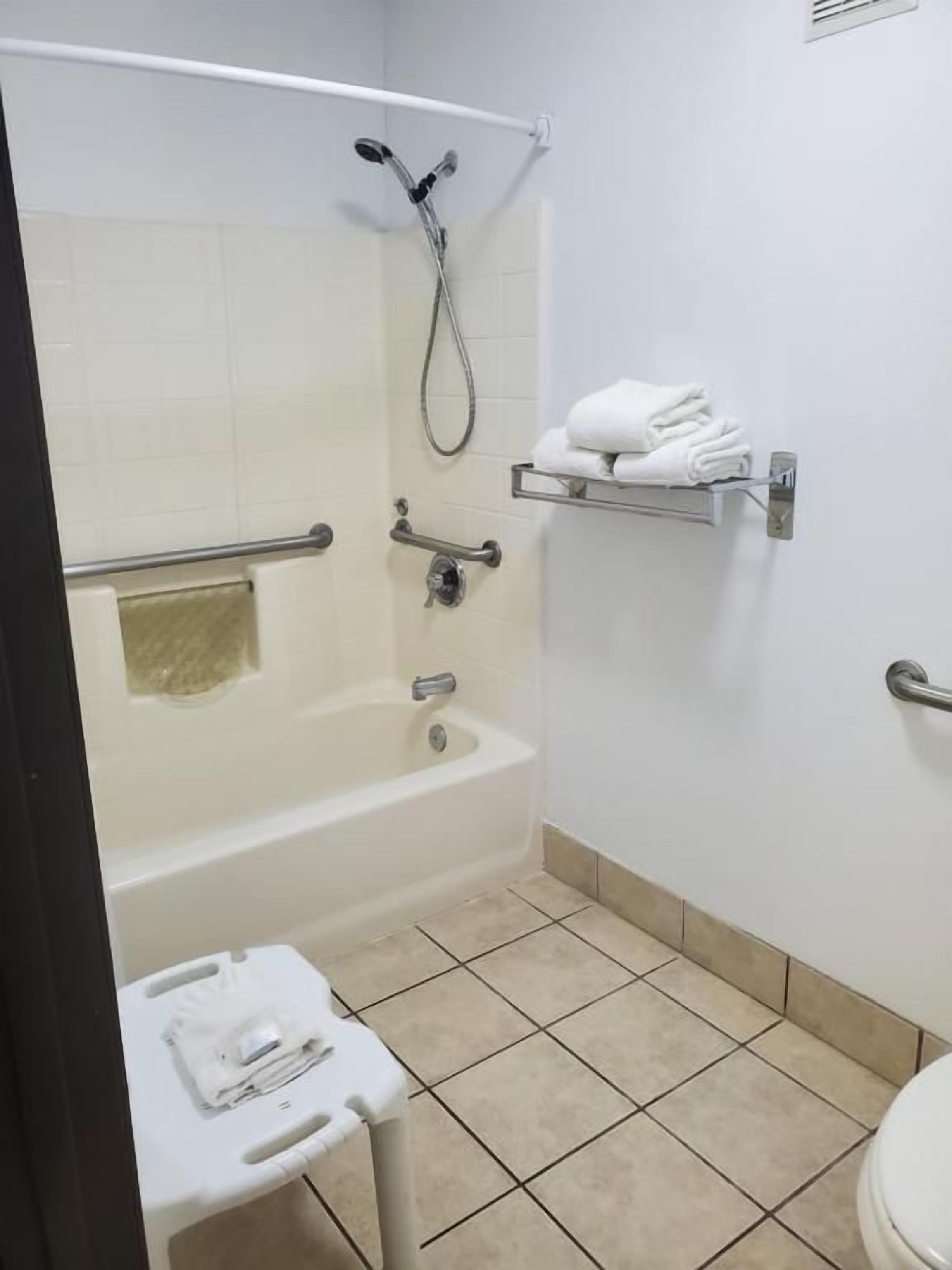 Un baño con bañera, ducha, inodoro y baranda.