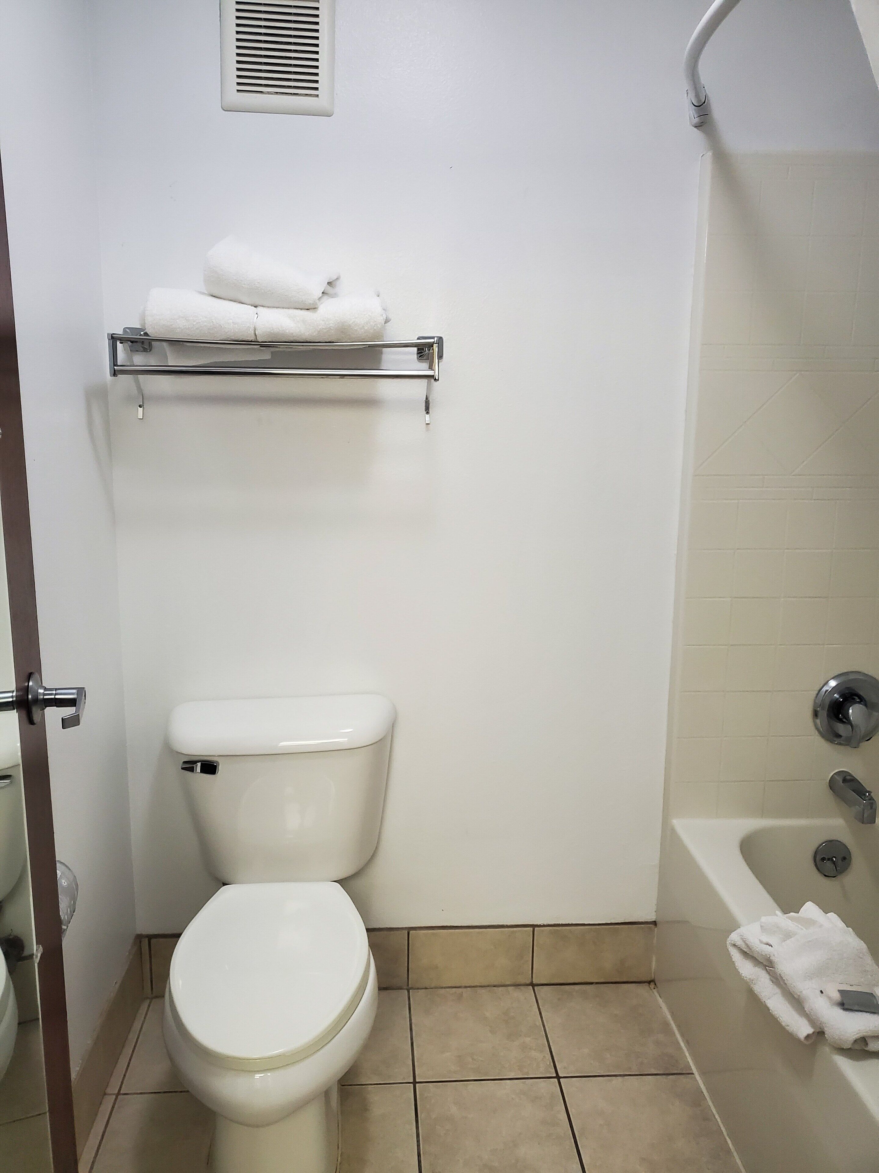Un baño con inodoro, toallero con toallas, zona de ducha y bañera.