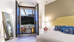Un dormitorio con una cama grande, una mesita de noche, un espejo y vistas a un balcón con mesa y sillas.