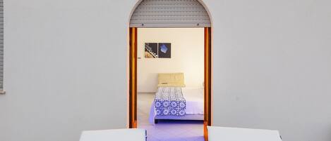 A bedroom with a bed, a window, and a door.