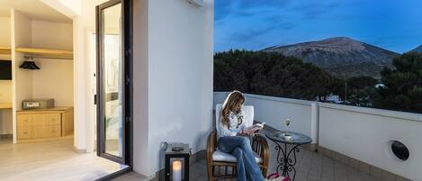 Un balcón con vistas a la montaña, una mesa con una vela y una silla.