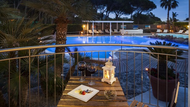 Zona de comedor junto a la piscina, con una mesa dispuesta para dos, con vistas a la piscina.
