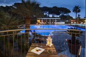 A poolside dining area with a table set for two, overlooking a pool. - Orsa Maggiore Hotel (Lipari)