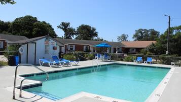 Una piscina al aire libre de temporada, sombrillas, tumbonas