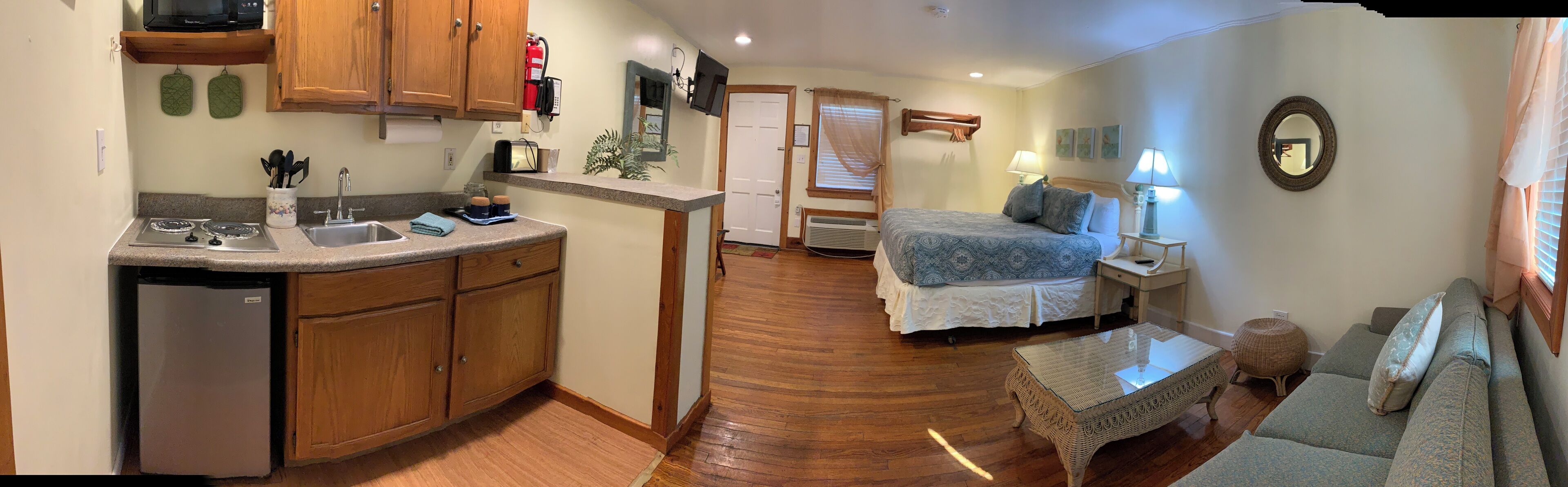 A compact living space with a kitchenette, a bed, a small table, and a sofa.