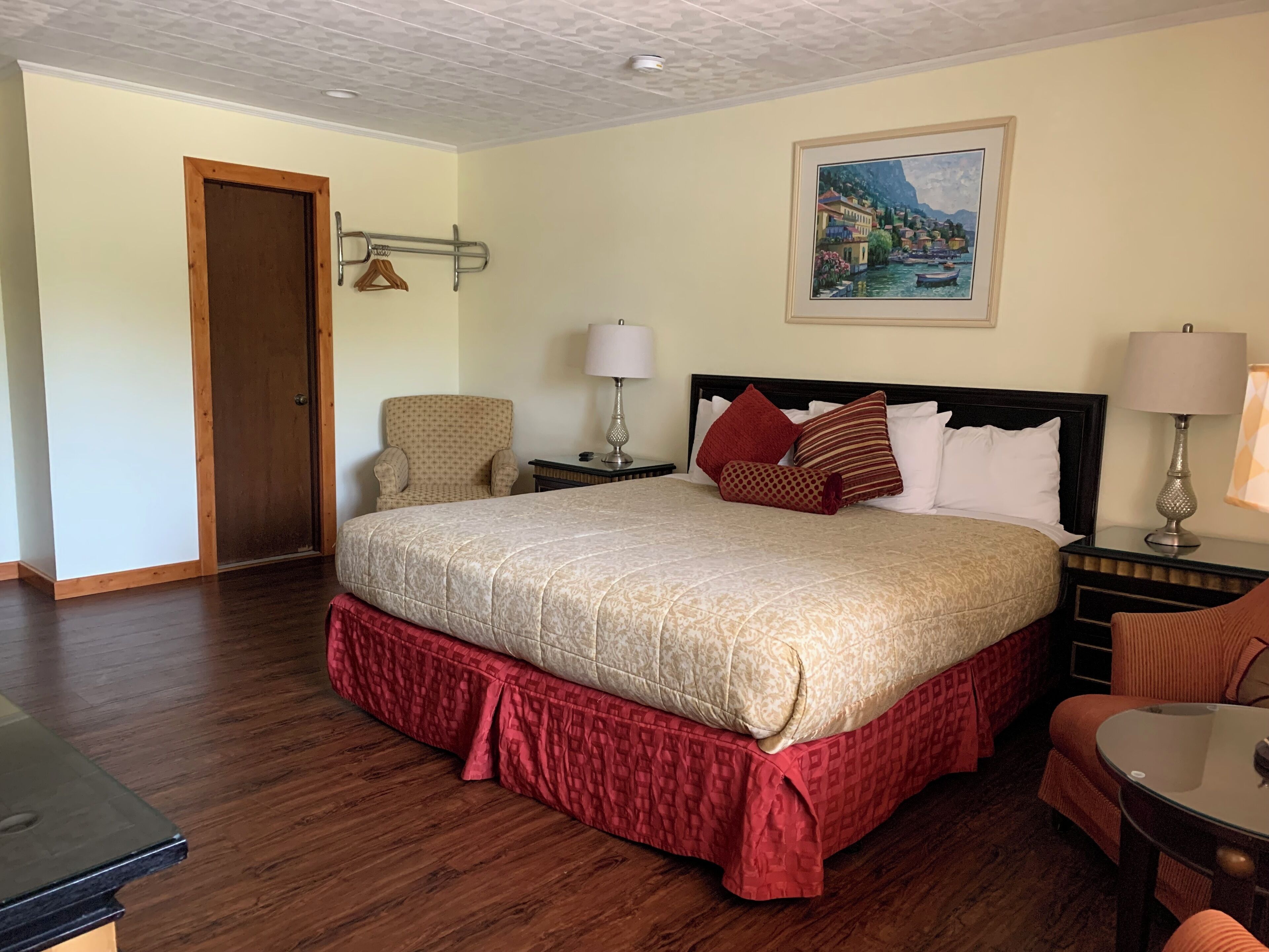 Un cuarto de hotel con una cama grande, una silla, una mesa y un cuadro en la pared.