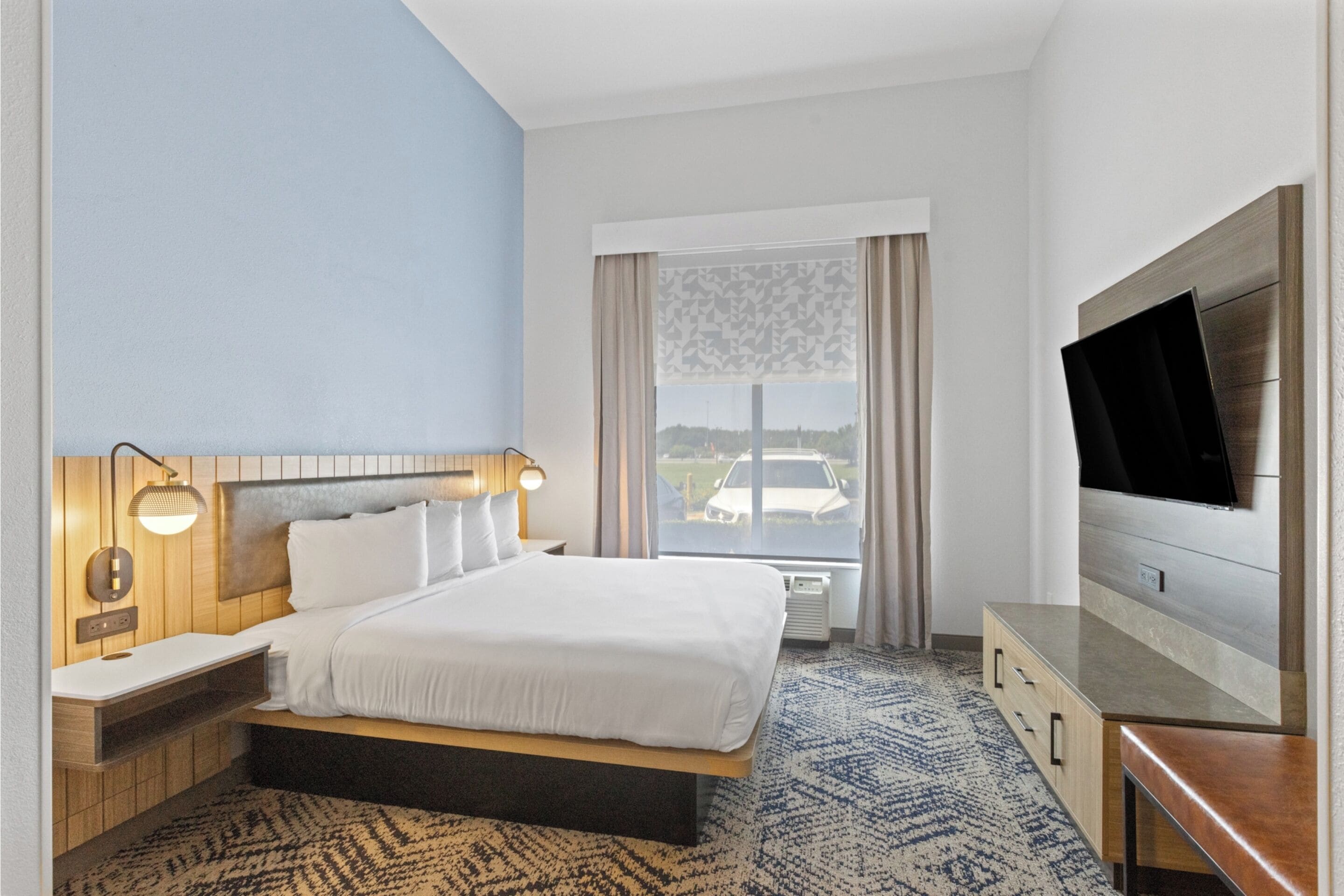 Une chambre d’hôtel avec un grand lit, des tables de chevet, une télévision et une fenêtre donnant sur un beau paysage.