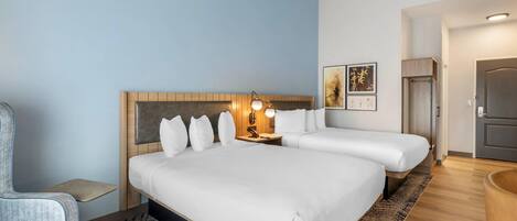 Una habitación de hotel con una cama grande, mesitas de noche, una silla y una pequeña mesa.