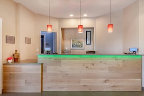 A reception desk with a wooden finish, pendant lighting, and a green-lit counter. - Country Inn & Suites by Radisson, Savannah Airport, GA (Savannah)