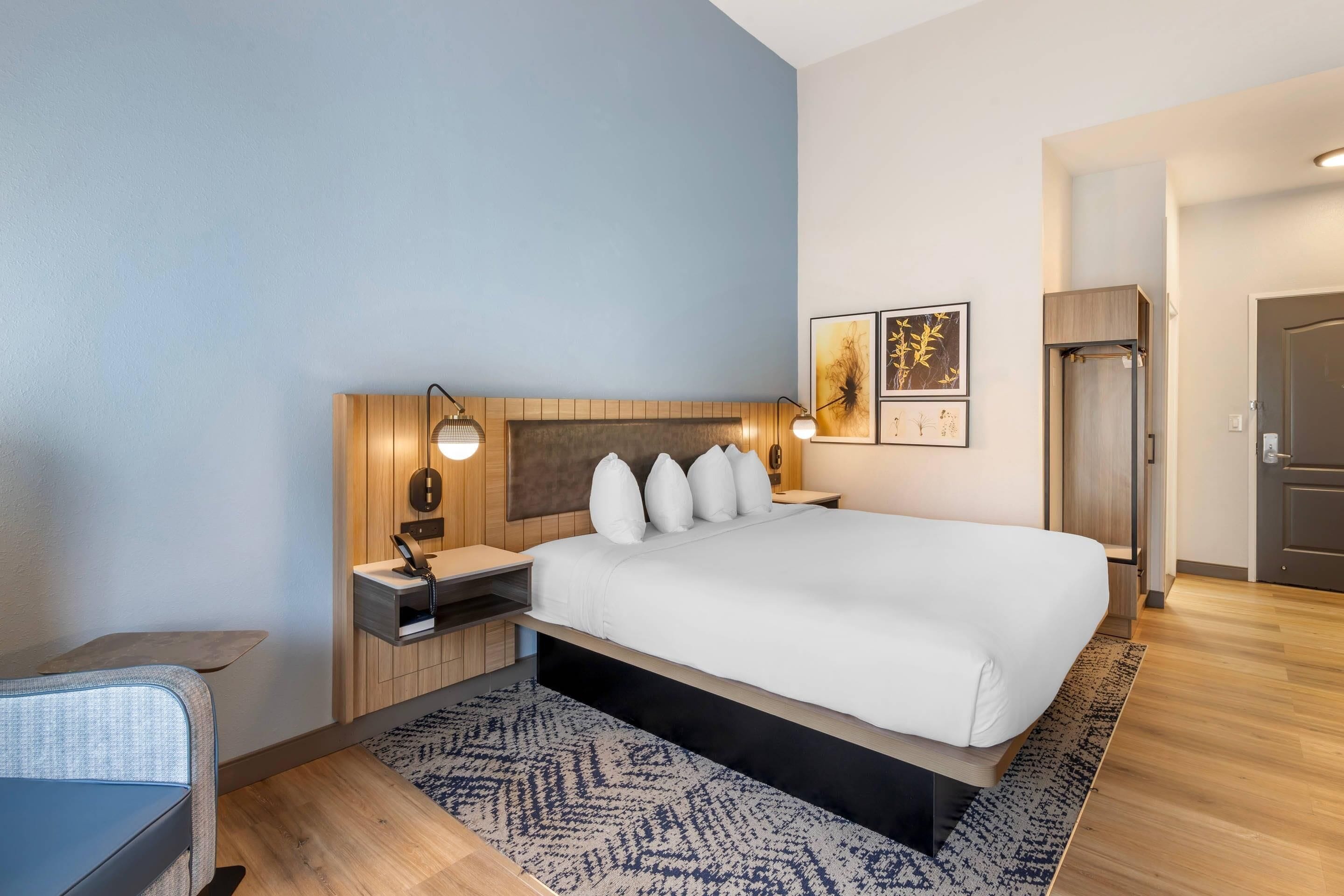 A modern hotel room with a large bed, bedside tables, a desk, and a chair.