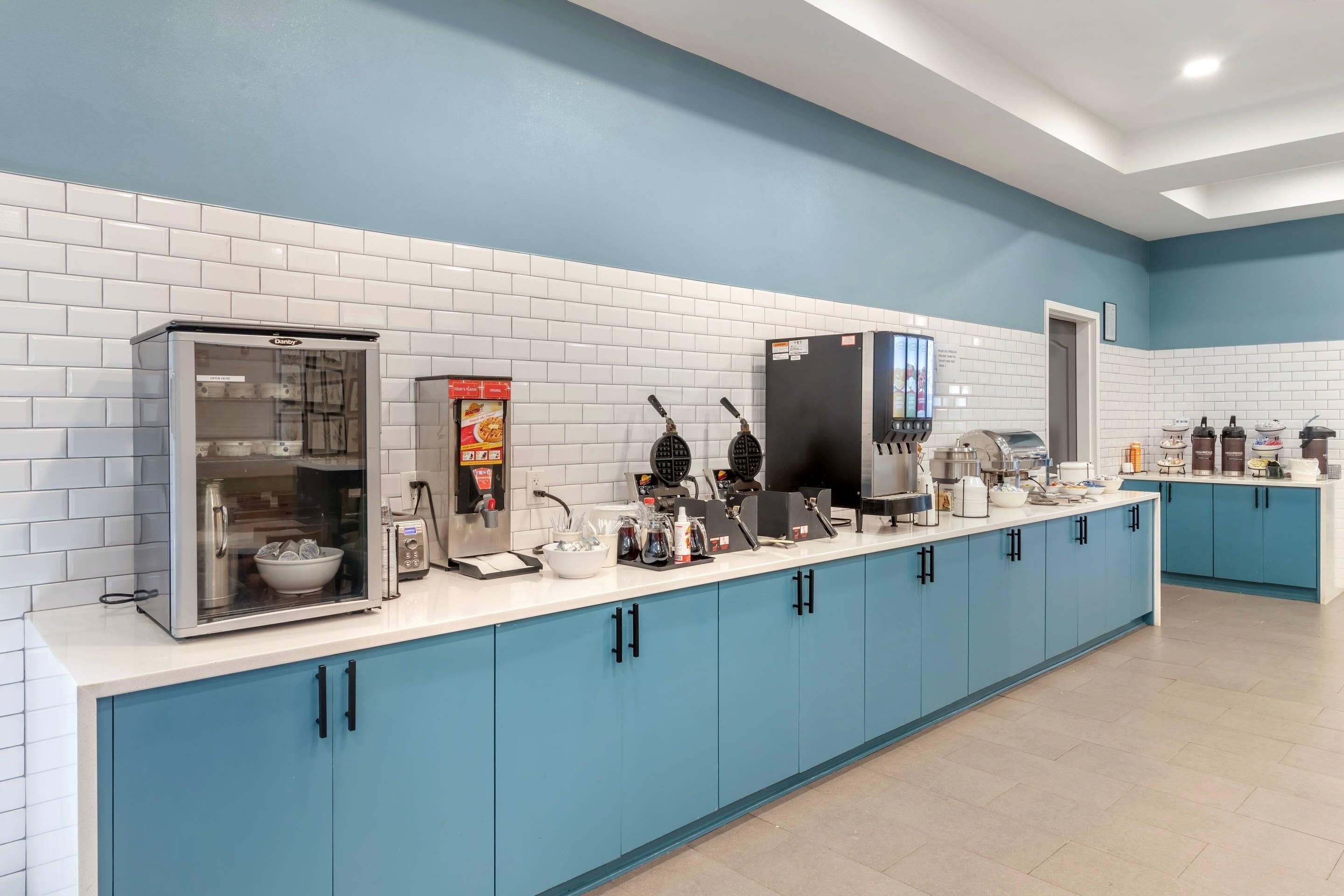 A modern kitchen with a microwave, waffle maker, coffee machine, and a refrigerator.