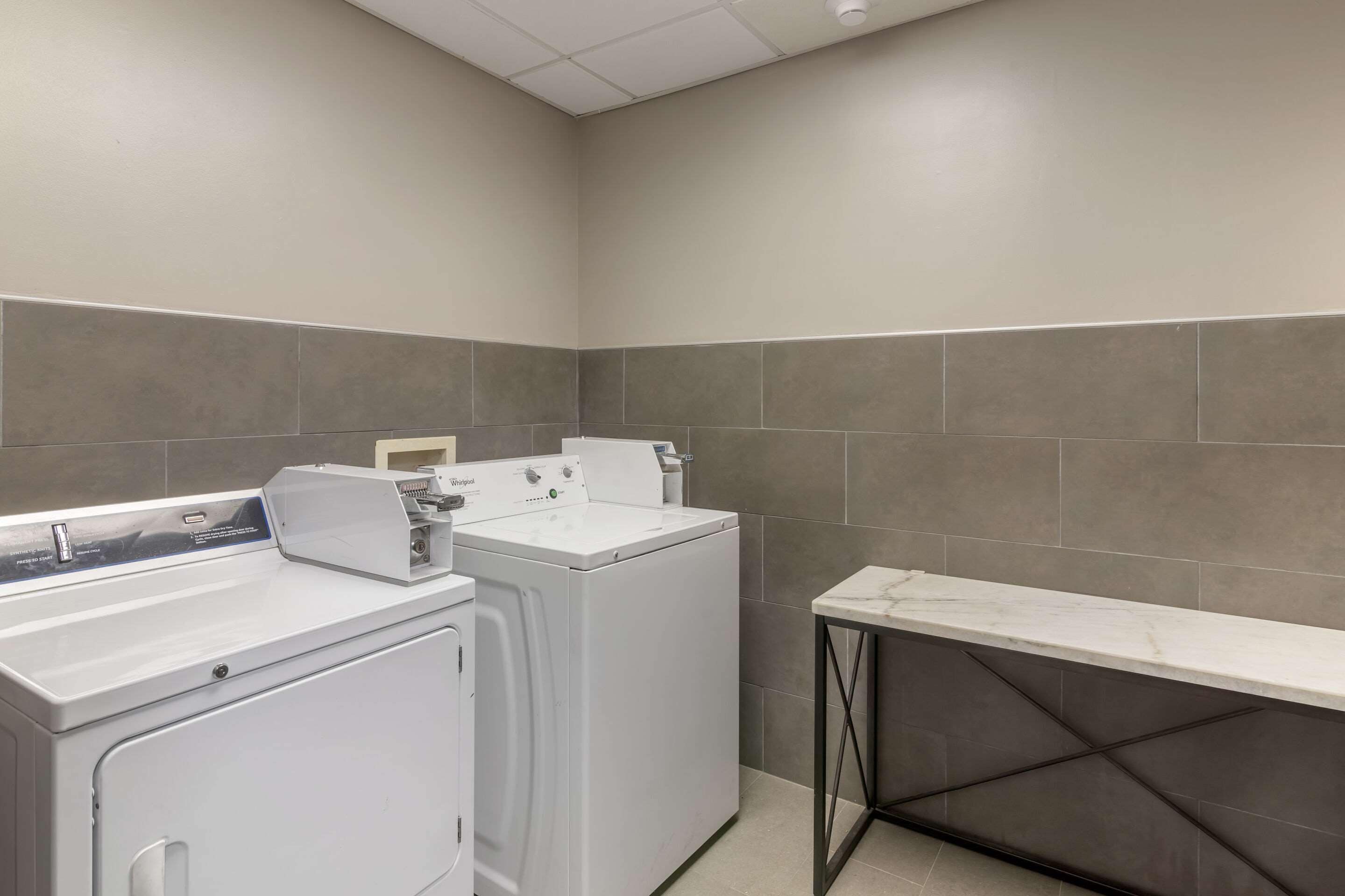 A laundry area with a white washing machine, a dryer, and a marble countertop.