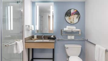 A modern bathroom with a glass shower enclosure, a wooden vanity with a sink, a toilet, and a towel rack.